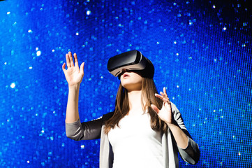 a beautiful girl wearing a virtual reality device, standing on the background of the sky