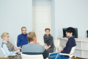 People sitting in circle during group therapy session with their mentor listening