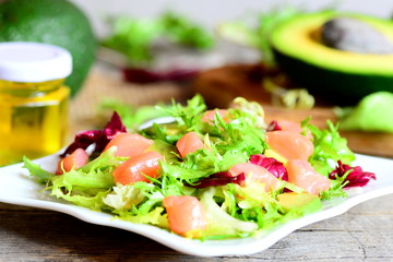Mixed green salad with smoked salmon and avocado and  dressing with olive oil and lemon juice. Vegetarian and quick salad on a plate. Vintage style. Closeup 