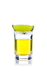 Shot of golden tequila with lime on a white background for isolation