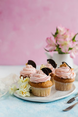 Vanilla cupcakes with chocolate chip cookies, decorated with flowers on a pink background