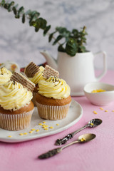 Spring yellow cupcakes with wafer and chocolate chips on marble background (close-up)