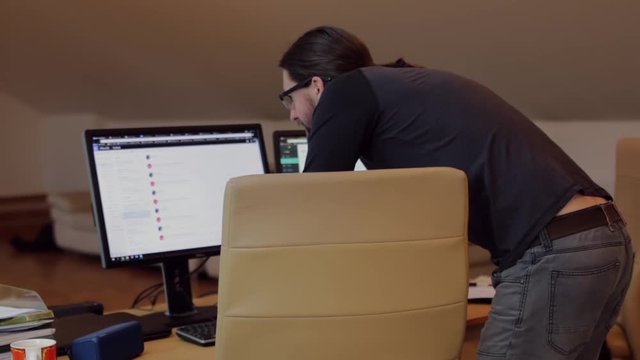 Bearded man working in office with 2 monitors