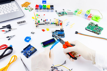Engineer is working wiith pliers and wires. Microcontrollers, chips, resistors and light-emitting...