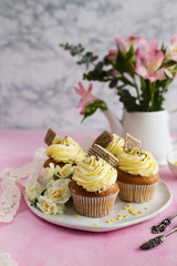 Delicious cupcakes with yellow cream on a pink background