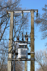 High voltage Power Transformer mounted on two concrete poles in forest - spring time