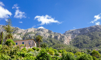 Fototapeta na wymiar Stone house with lush garden in Mallorca with mountain view