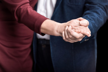 Fototapeta premium Close-up partial view of senior couple holding hands while dancing