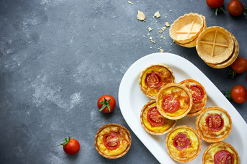 Cheese tomato tartlets , puff pastry appetizers , mini-pizzas with cheese and cherry tomatoes