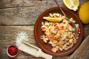 Lemon rice with slices of salmon fillet on old wooden background