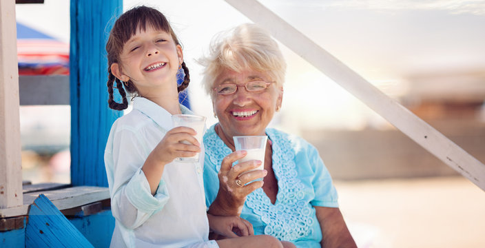 Grandmother with granddaughter drinking milk outdoors