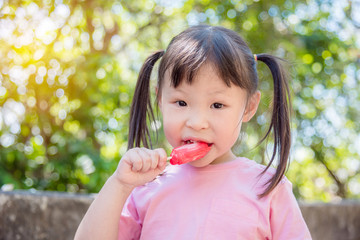 Little asian girl eating ice cream in park