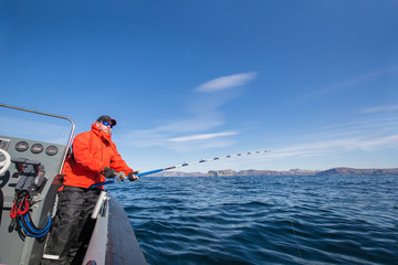 Fototapeta premium man with a fishing rod in his hands. Red Jacket. sports glasses. fisherman