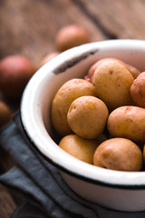 Raw potatoes in the metal bowl vertical