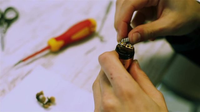 Male hands preload coils of the electronic cigarette. Vape after-sales service. Vaping. ENDS.