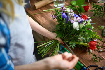 Florist tying floral bouquet with ribbon