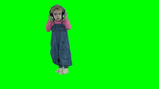 Cute girl take off huge headphones off head isolated on green background