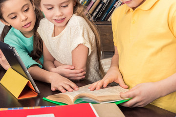 Cropped shot of schoolchildren studying with book and digital tablet