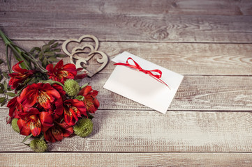 Red freesia with blank message card on a wooden horizontal background. romantic story. Chocolate retro toning