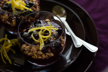 Healthy breakfast: blackberry and banana smoothie with granola on magenta plate. Selective focus