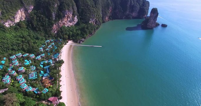 Aerial view flying over amaizing hotel houses towards beautiful green mountains and white sandy beach. Krabi island, Thailand