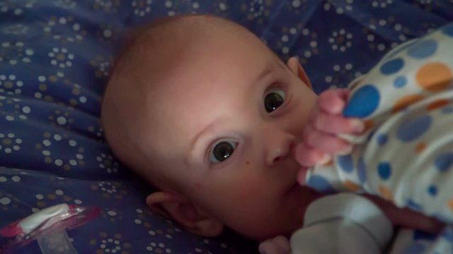 A small baby girl has very beautiful green eyes. She just woke up and she looks very happy.
