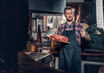 A man holds beef steak on a kitchen.