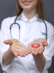 
Blurred  woman doctor figure with two condoms on palms. Conceptual  cropped image 
