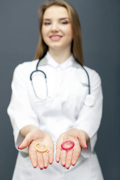 
Young woman doctor figure with two condoms on palms. Conceptual  cropped image 
