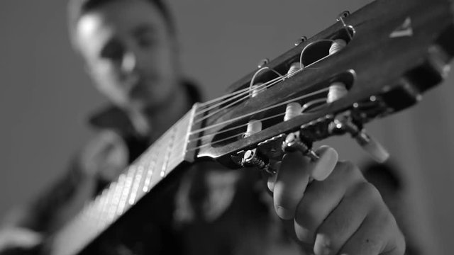 Guitarist tuning the acoustic guitar - monochrome