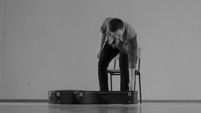 Guitarist gets a guitar out of the case and begins to play - monochrome