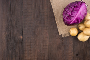 Purple cabbage, potatoes on old dark wood table.