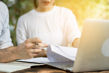 Business man and women working in the garden with laptops.