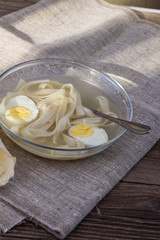 cup of chicken soup with noodles and eggs