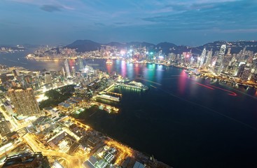 Fototapeta na wymiar Aerial view of Hong Kong & Kowloon (Tsim Sha Tsui) at night with city skyline of crowded skyscrapers by Victoria Harbour & light trails of ships across seaport~ Cityscape of Hong Kong in blue twilight
