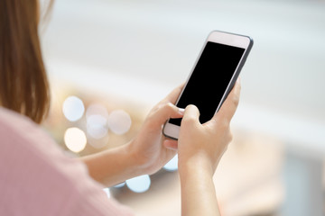 Young woman using smart phone with hands on bokeh background.