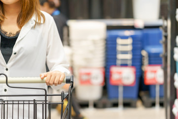 Hands of woman holding shopping cart in supermarket.