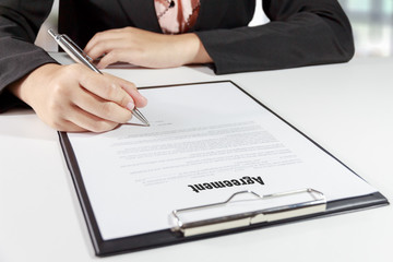 Hands of business woman signing the agreement document with pen on desk - business concept.