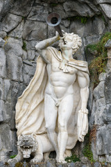Statue of satyr with a pipe in hand and a lion at feet in Mountain park Wilhelmshoehe, Germany