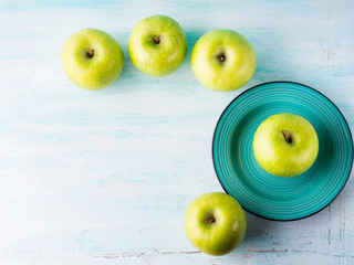 Green pastel background with apples flowers. Healthy food concept backdrop for writing text. Top view