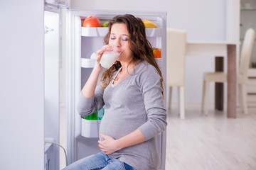 Pregnant woman near fridge looking for food and snacks