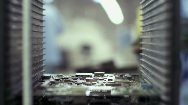 Hand of a Technician placing Printed Circuit Boards into a Rack Holder Inside a Computer Factory. Close Up.