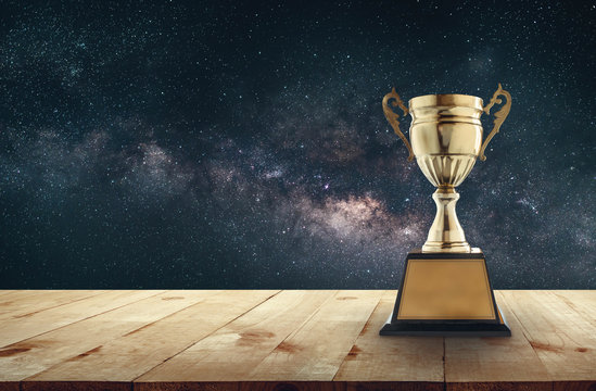 champion golden trophy on wood table with Milky Way background copy space  ready for your design. Stock Photo | Adobe Stock