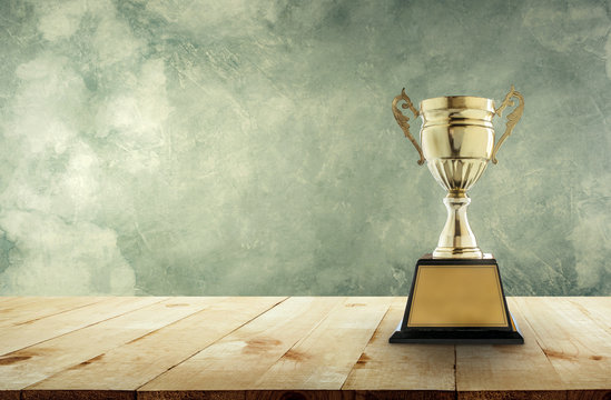 champion golden trophy placed on a wooden table with vintage wall background  copy space ready for your design. Stock Photo | Adobe Stock