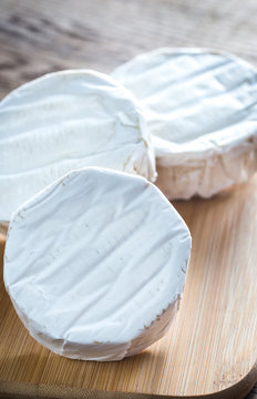 Three heads of Camembert cheese on the wooden board
