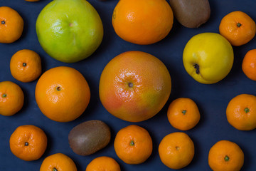 many beautiful bright juicy ripe delicious mouth-watering citrus fruits are are dark blue on a black background scattered freely close-up macro