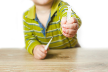 child hand holding a syringe