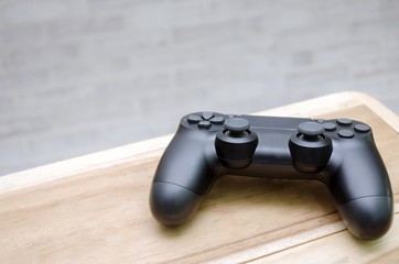 Video game controller on wooden desk with brick  wall background, copy space for text, color tone effect.