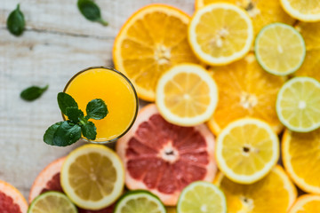 Fototapeta na wymiar glass of orange juice on the wood background with slices of citrus
