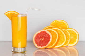 glass of orange juice on the white background with slices of citrus